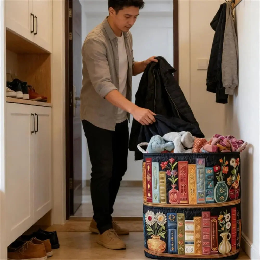 A person is placing a black garment into a round, tiered laundry basket decorated with floral patterns.