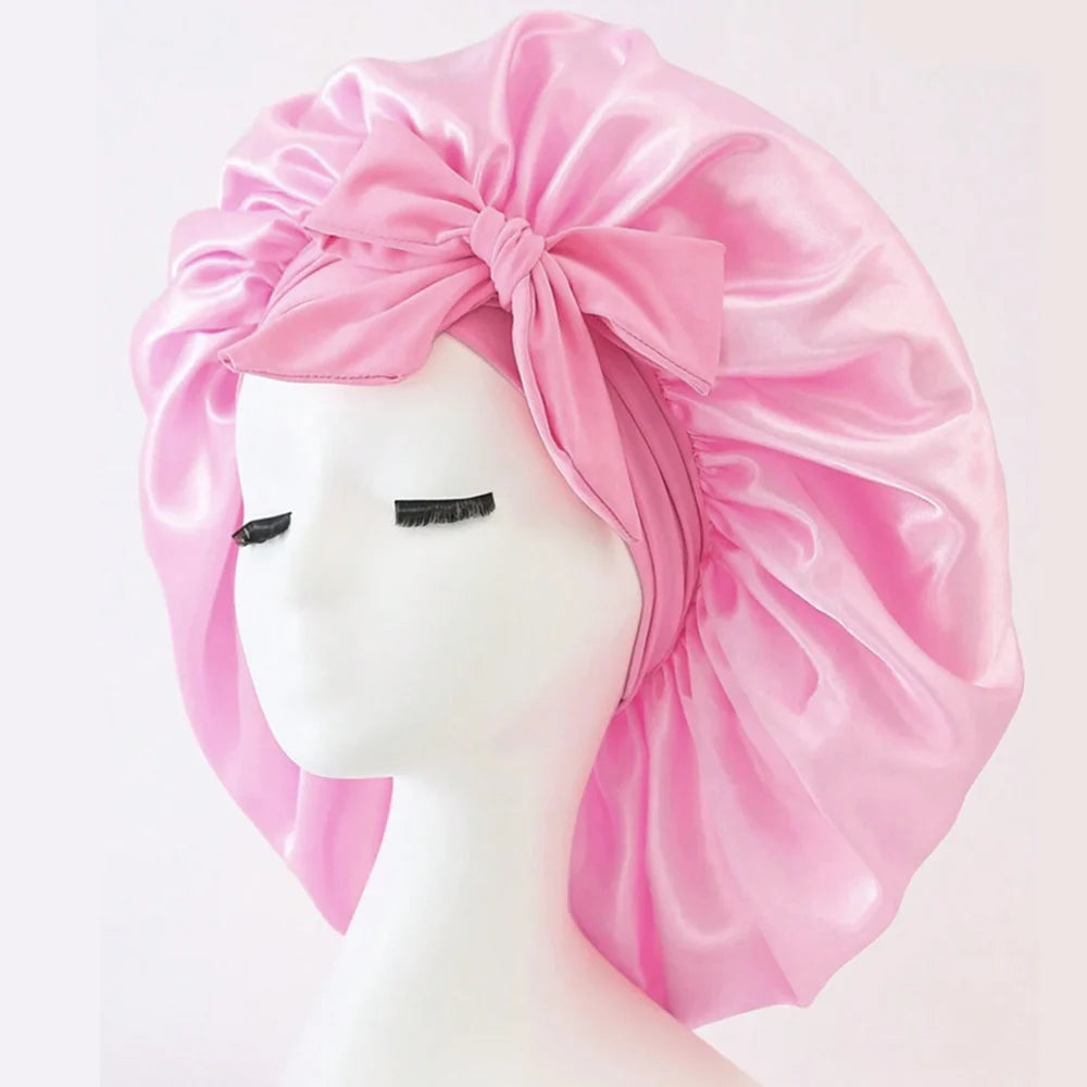 Rosa Satin-Seiden-Haube mit großer Schleife auf weißem Mannequin-Kopf.