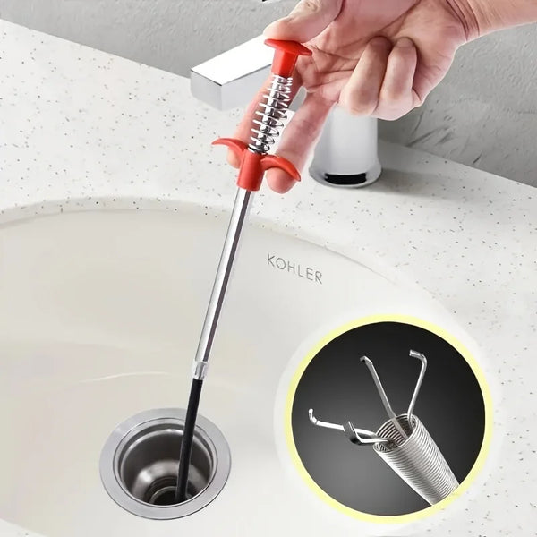 A hand is shown using a red bendable drain auger with a claw hook to clear debris from a Kohler sink.