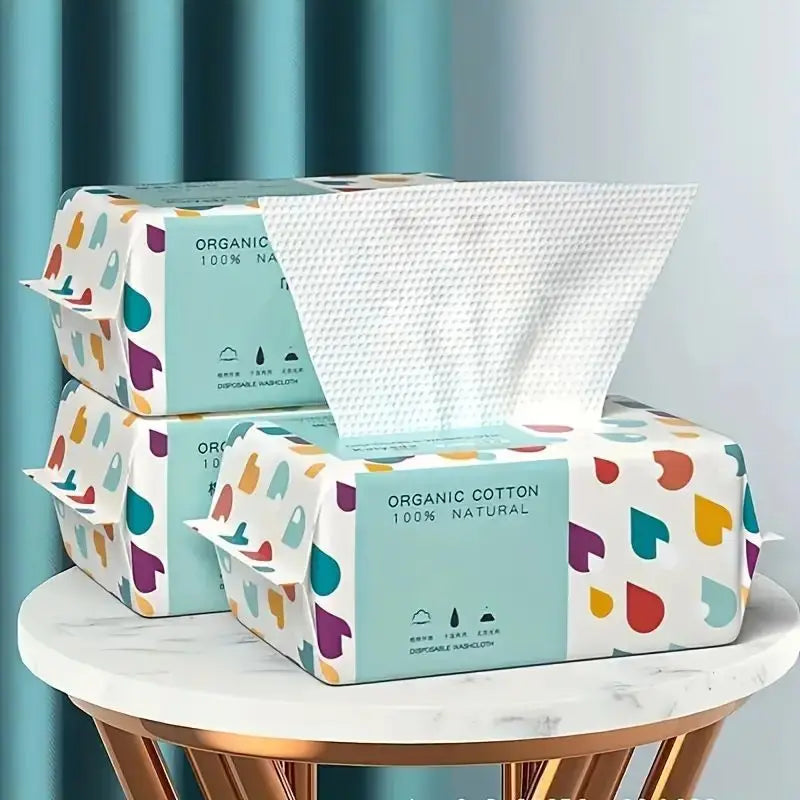 Karton mit wiederverwendbaren Bio-Baumwoll-Gesichtstüchern in farbigem Verpackung, auf weißem Tisch.