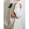 A close-up of a white blazer with a gold chain strap and a pink patterned magnetic crossbody bag.