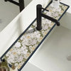 A black faucet mounted on a white countertop with a floral patterned mat.