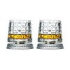 Un par de vasos de whisky giratorios con cristal transparente y líquido ámbar dentro.