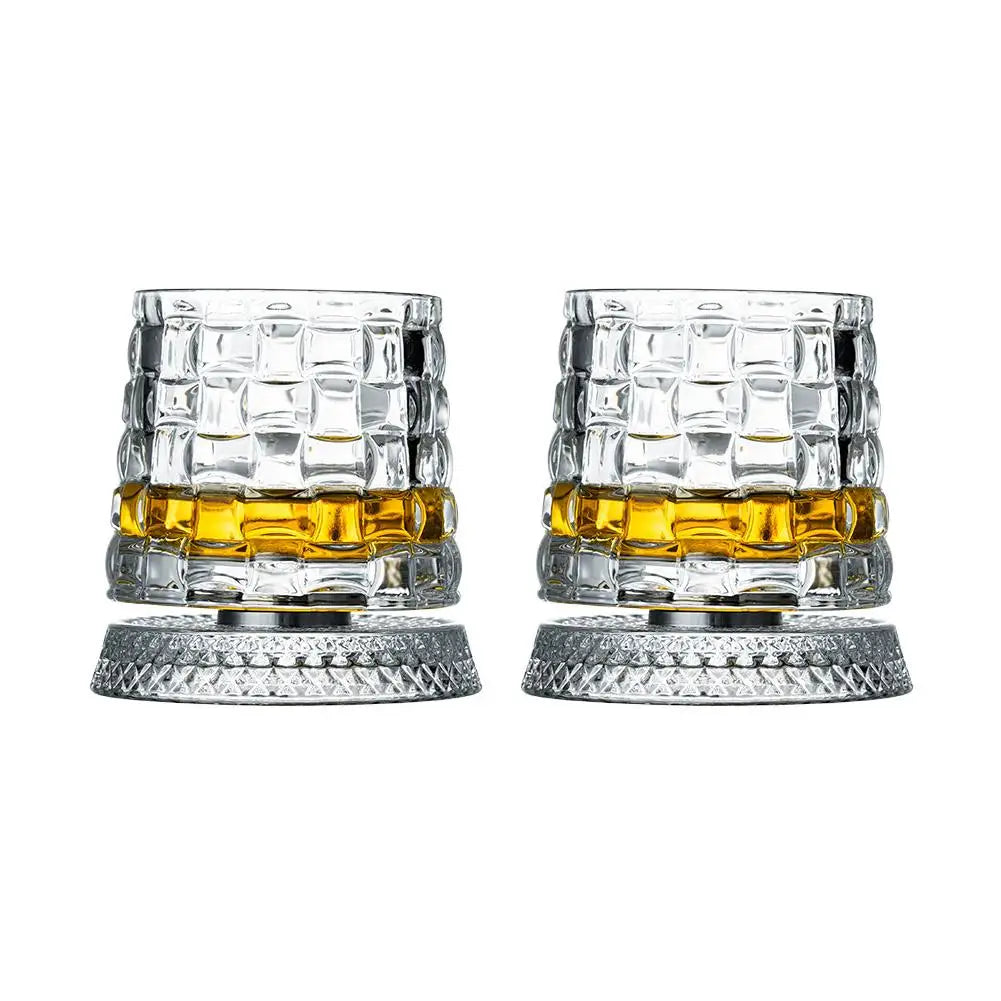 Un par de vasos de whisky giratorios con cristal transparente y líquido ámbar dentro.