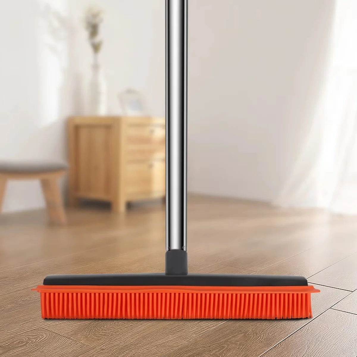 A close-up view of an adjustable rubber broom with a squeegee head resting on a wooden floor.