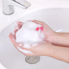Hands holding a white exfoliating mesh soap pouch with a red accent on a white sink