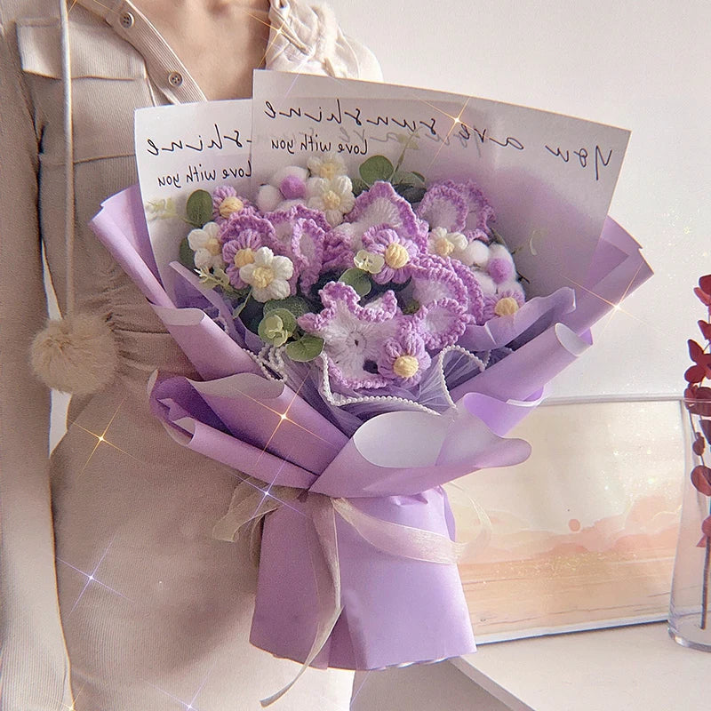 Un bouquet de carancisses en coton violet fait main, emballé dans du papier lilas, tenu par une personne.