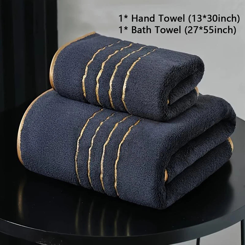A stack of dark blue hand and bath towels with gold striped edges displayed on a black surface.