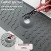A silicone kitchen sink splash guard mat with a custom aperture being cut by scissors.