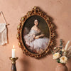 Ölgemälde in vergoldetem Rahmen mit einer Frau in weißer Spitze und fließendem Kleid an einer beige Wand.