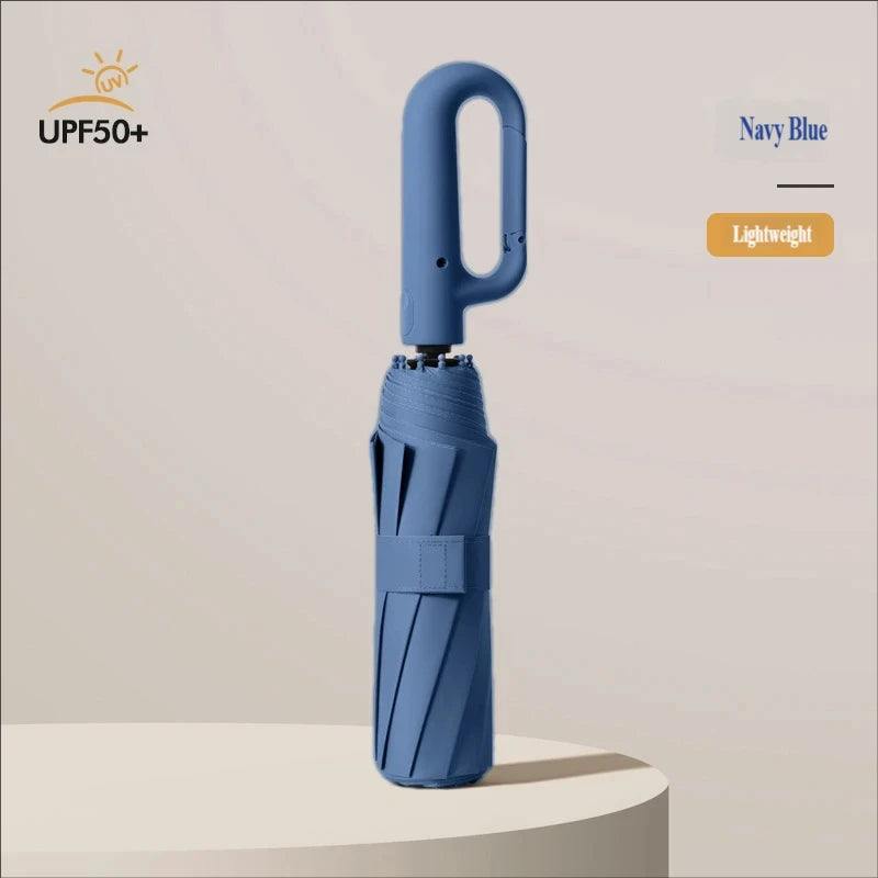 A navy blue large automatic folding umbrella is shown standing upright on a light surface.