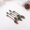 A set of natural crystal spoons with purple and blue stones resting on a white surface.