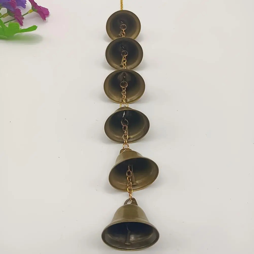 A vertical arrangement of vintage metal wind chimes with brass chains and dome-shaped metal bowls.