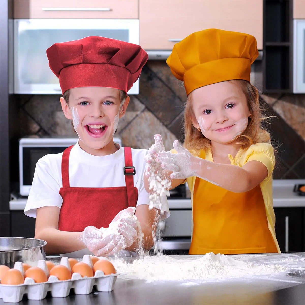 Two children wearing chef hats and aprons are mixing flour on a table.