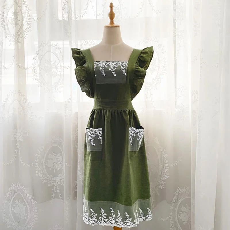 A green linen kitchen apron with white lace detailing displayed on a mannequin.