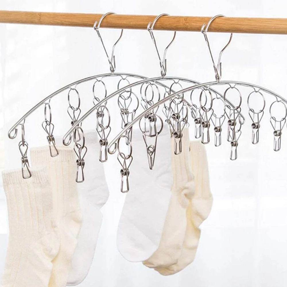 A multi-clip clothes drying rack hanging from a wooden bar, with white socks and underwear visible.