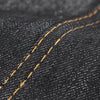 Close-up of dark denim fabric showing a stitched seam with a visible orange thread on an adjustable tool apron.