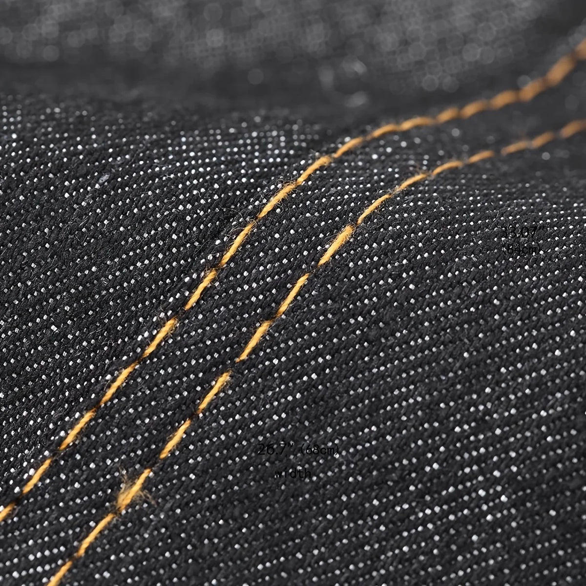 Close-up of dark denim fabric showing a stitched seam with a visible orange thread on an adjustable tool apron.