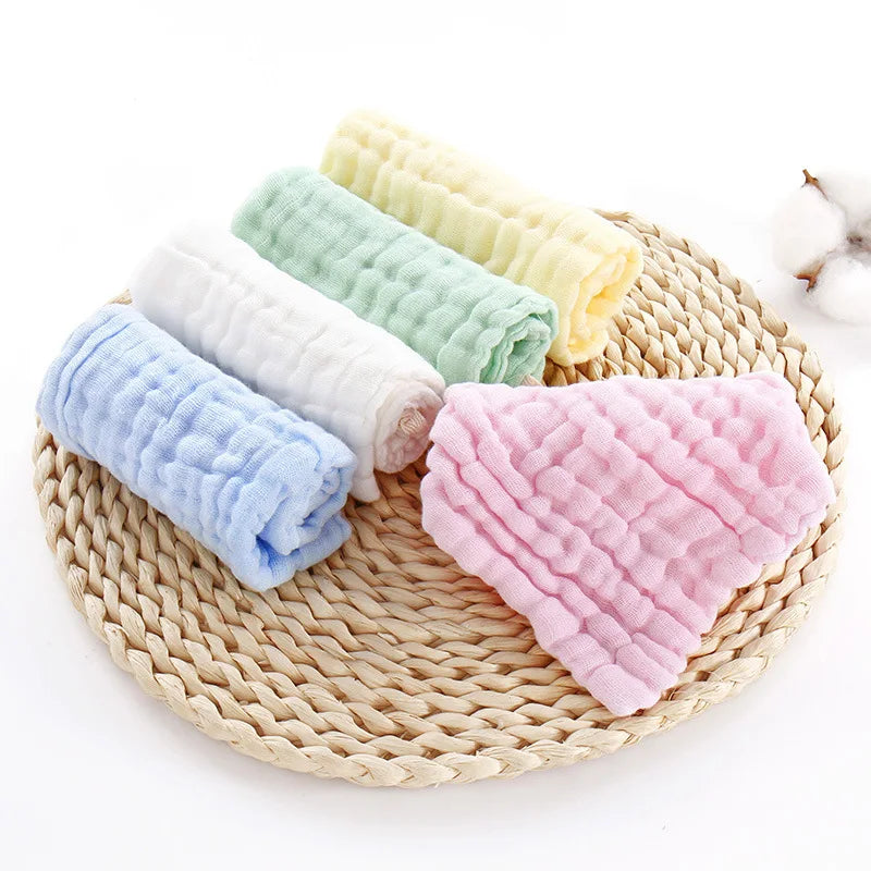 Una pila de cinco toallitas húmedas orgánicas de algodón para bebé y cara en colores pastel, incluyendo blanco, azul claro, v