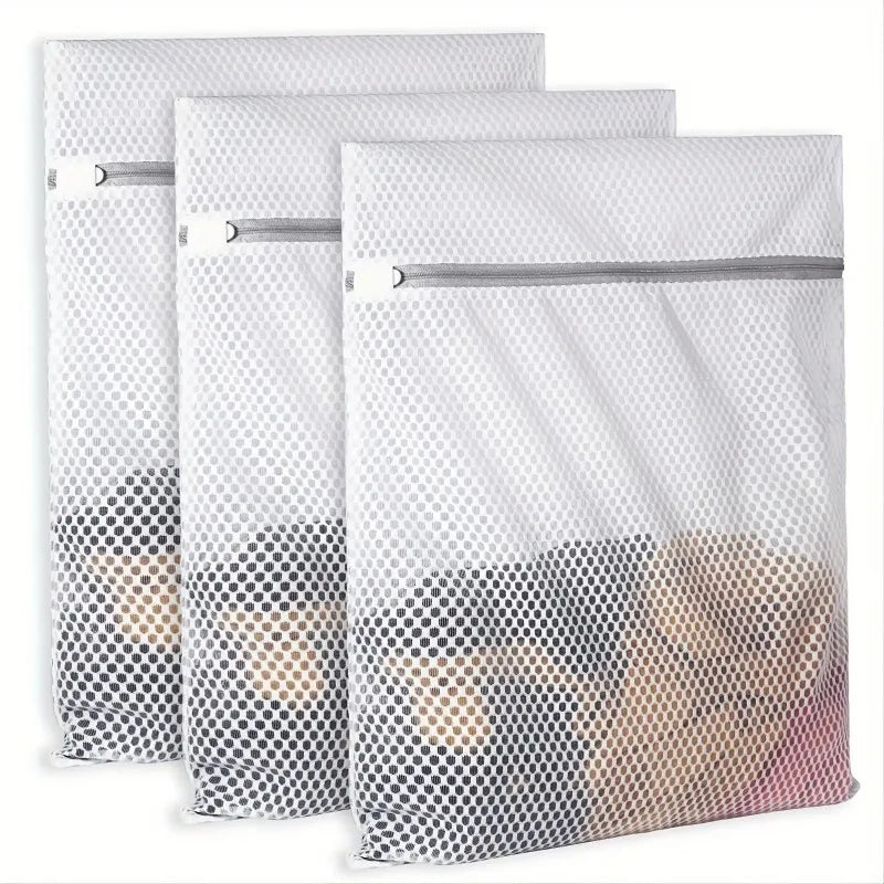 Three white reusable honeycomb mesh laundry bags stacked together.