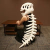 A person wearing a realistic white dinosaur skeleton costume, posed next to a wooden table.