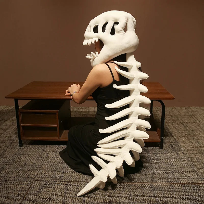 A person wearing a realistic white dinosaur skeleton costume, posed next to a wooden table.