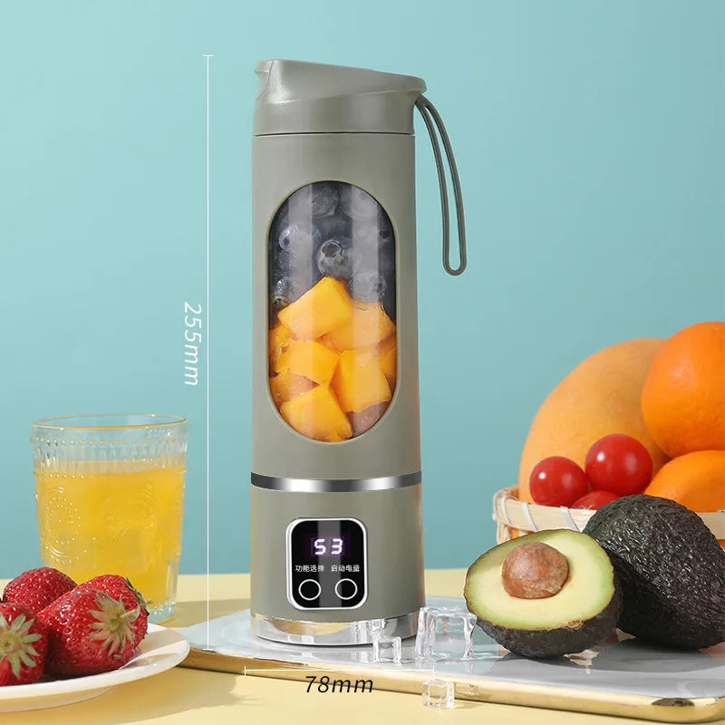 Licuadora exprimidora de frutas eléctrica portátil en gris junto a fruta fresca como naranjas, fresas y aguacate.