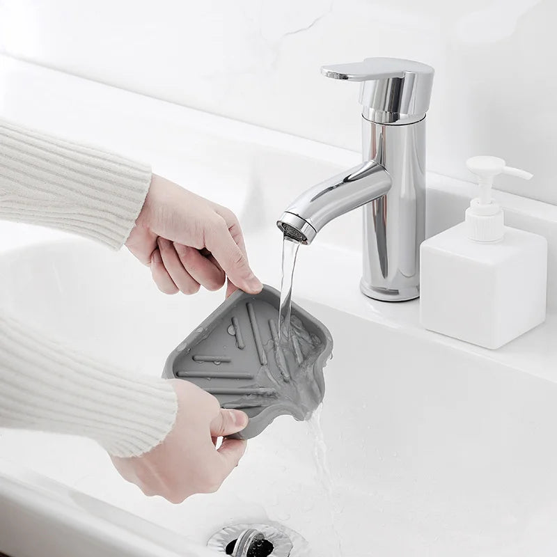 Eine Hand gießt Wasser aus einem Chromarmatur in eine Silikon-Waschschale in einer weißen Badezimmersink.