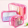 A set of three clear pink travel makeup organizer bags containing various cosmetic items.