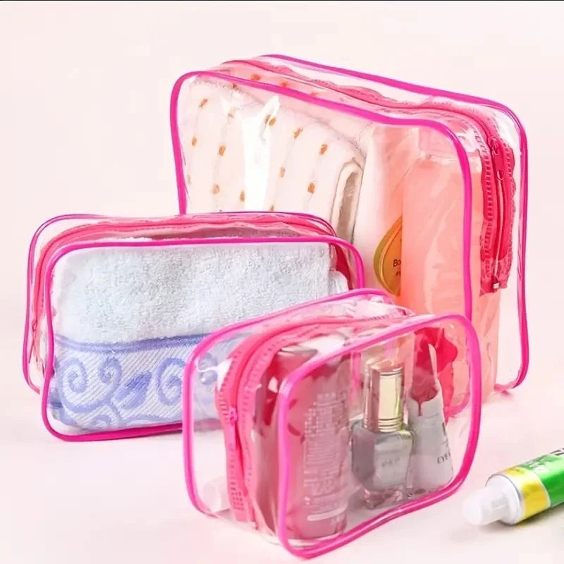 A set of three clear pink travel makeup organizer bags containing various cosmetic items.