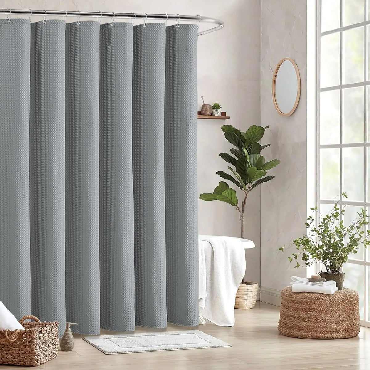 A set of gray waffle weave shower curtains hanging on a metal rod in a bathroom setting.