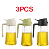 Three clear glass oil spray bottles with black and white tops filled with yellow cooking oil.