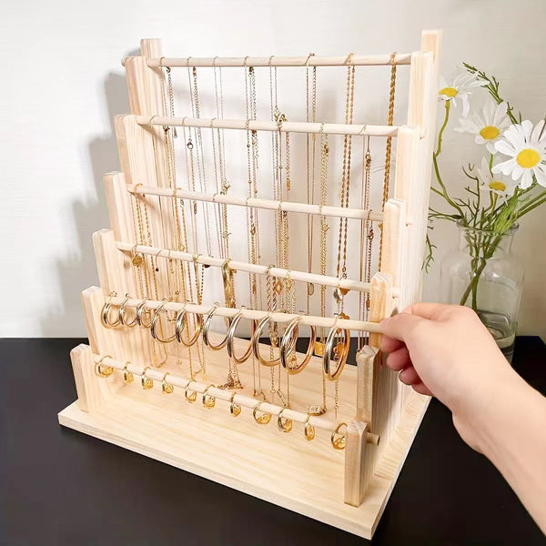 A wooden ladder jewelry organizer displaying various gold-colored necklaces and chains.