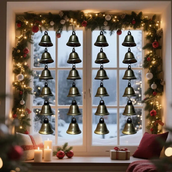 A vintage metal wind chime decoration hanging in a window decorated with festive greenery and lights.