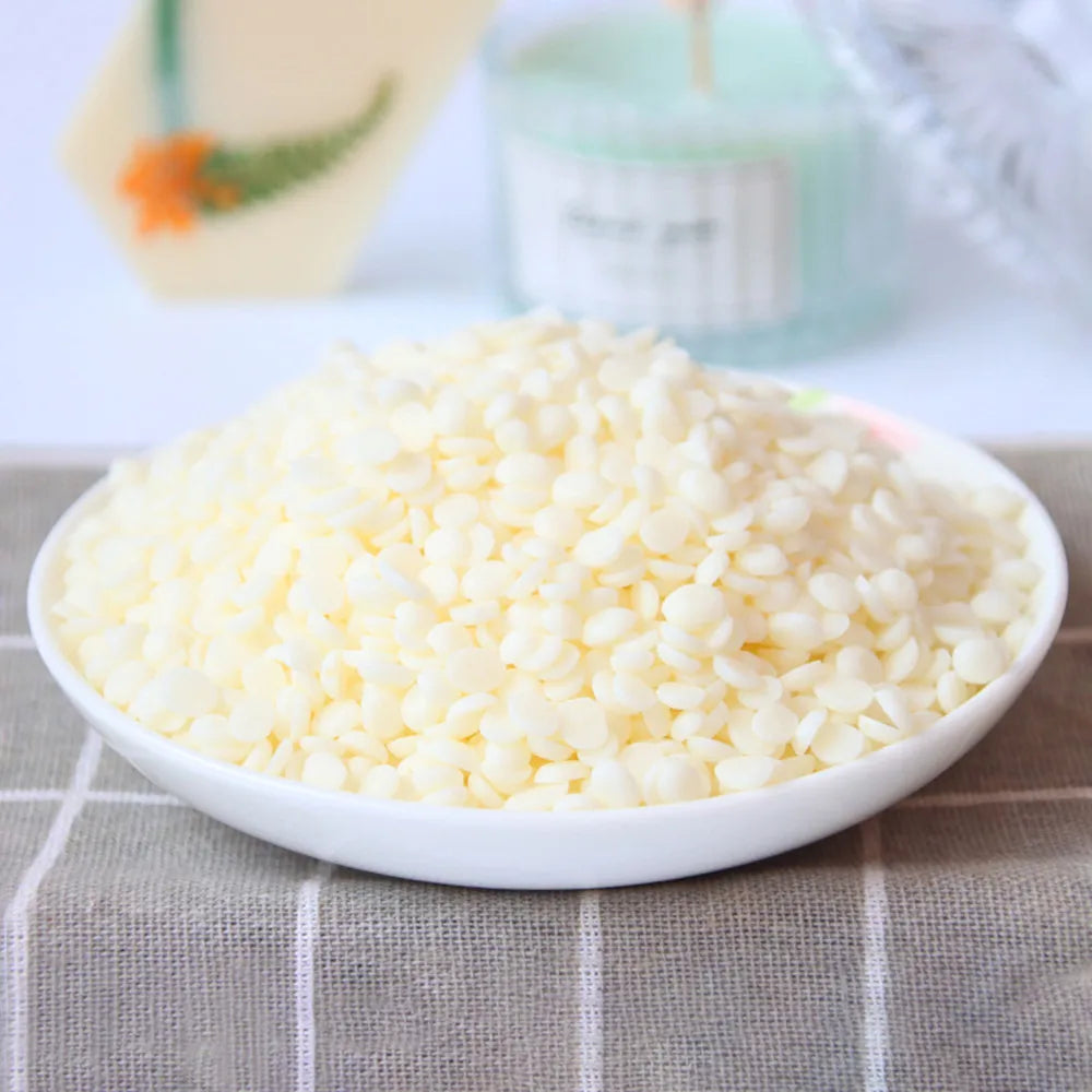 Una pila de gránulos de cera de soja natural blanca en un tazón blanco sobre una superficie de tela gris.