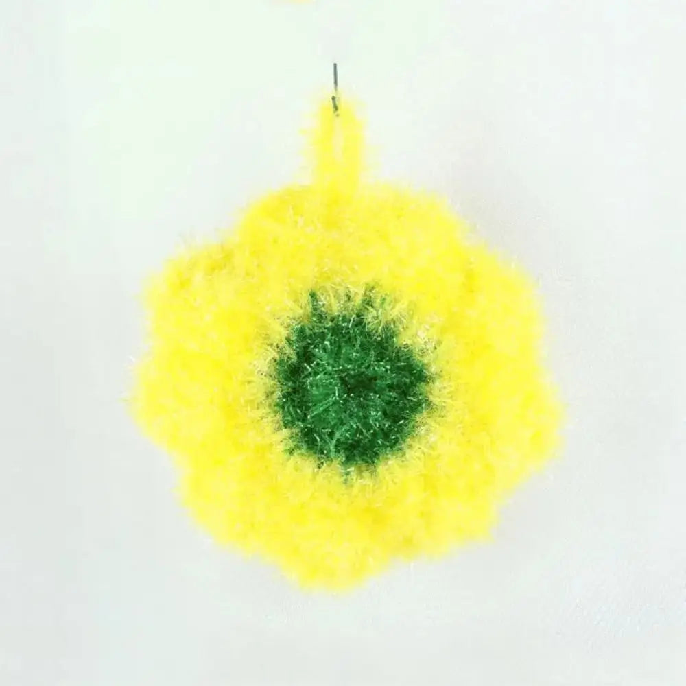 A bright yellow, fluffy flower-shaped dish towel with a green center.