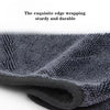 A close-up of a dark gray microfiber car cleaning towel rolled up, showing its textured surface.