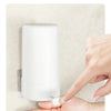 A hand is pressing the switch outlet on a white portable soap bar grinder with a wall-mount design.