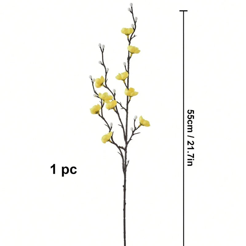 Eine schlanke Zweig künstlicher weißer Pflaumenblüten mit gelben Blüten neben einer Waage.