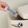 Eine Hand hält einen klaren magnetischen Toilettenreinigungsstab über den Rand einer weißen Toilettenschüssel.