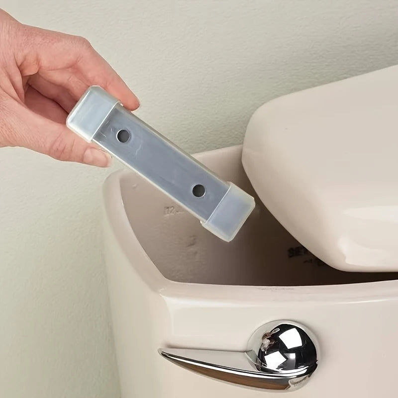 Eine Hand hält einen klaren magnetischen Toilettenreinigungsstab über den Rand einer weißen Toilettenschüssel.