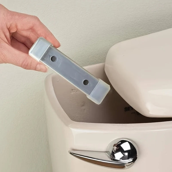 Eine Hand hält einen klaren magnetischen Toilettenreinigungsschiettel über die Öffnung einer weißen Toilettenschüssel.