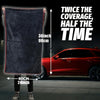 A person holds a dark gray microfiber car drying towel demonstrating its size and coverage over a red car.