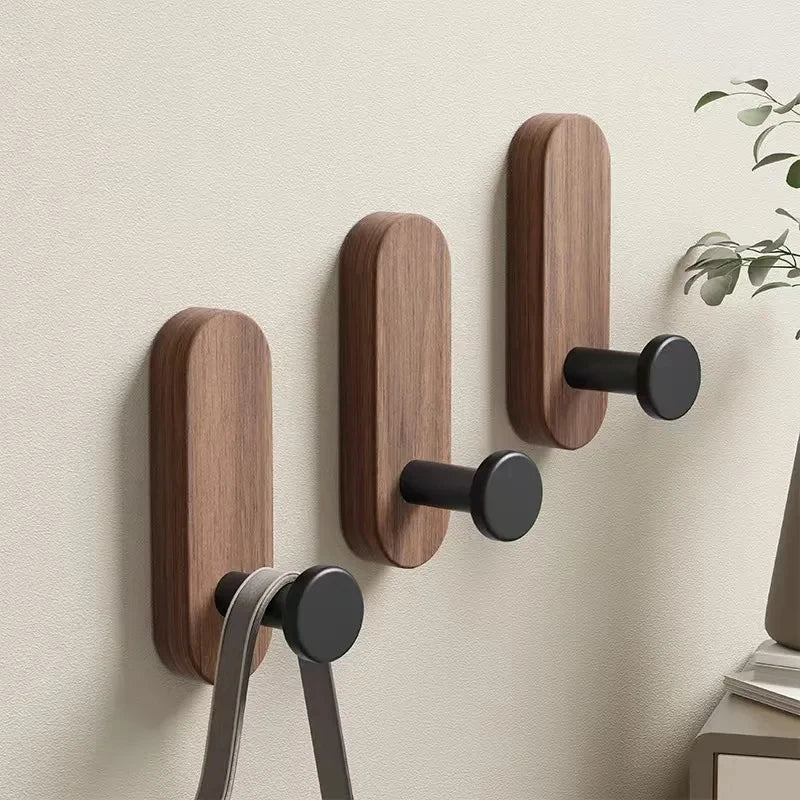 A set of wooden wall hooks with black mounting plates installed on a light-colored wall.