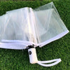 Automatic transparent folding umbrella with a white handle resting on green grass.