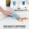A hand is using a blue microfiber cloth to wipe up a brown liquid on a white surface, demonstrating high absorbency.