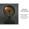 A round clock face with an orange dial and black hands, featuring a small night light function.