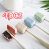 Four silicone toothbrush head covers in pink, blue, and green are displayed on a white marble surface.