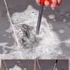 A hand uses a red drain cleaning tool to remove hair and debris from a drain, shown before and after cleaning.