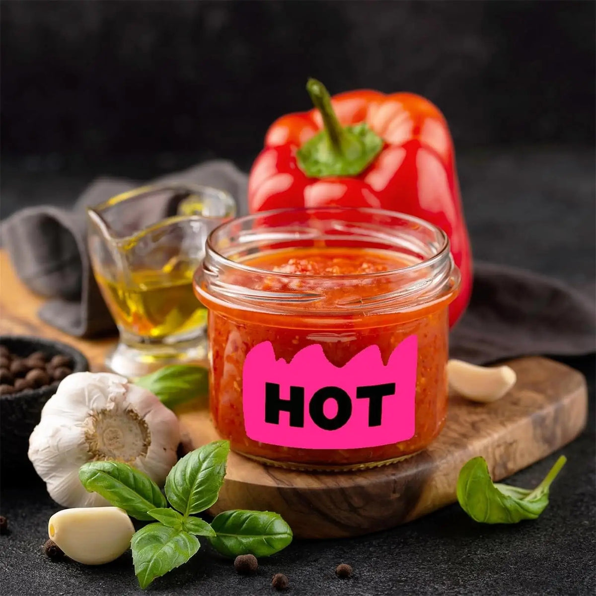 Jar of bright red hot sauce with a pepper in the background on a wooden board